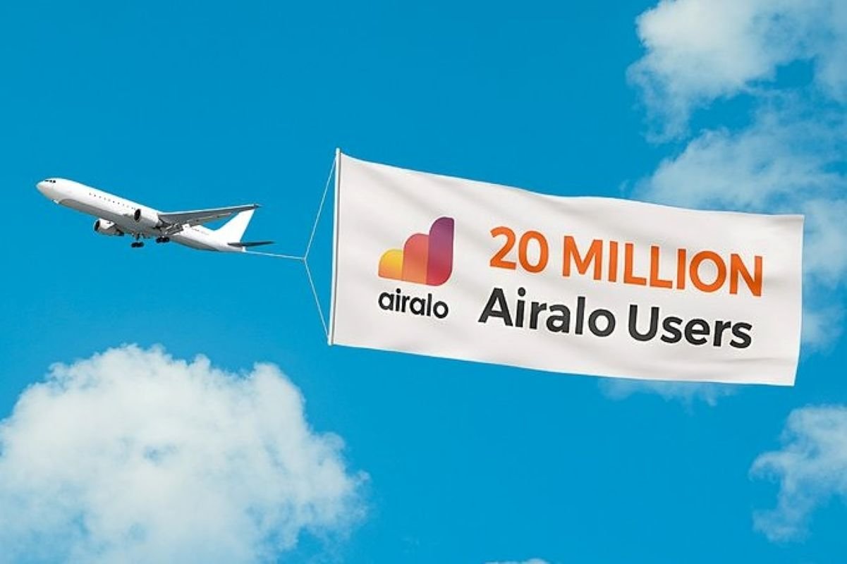 Airplane towing a banner that reads '20 Million Airalo Users' against a blue sky with clouds.