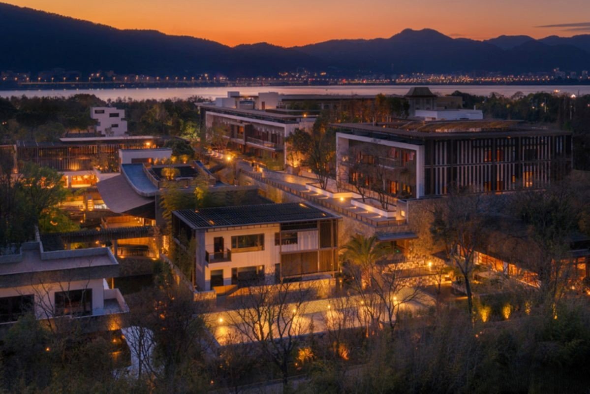 Aerial view of Songtsam Kunming hotel complex illuminated at dusk, showcasing modern architecture and landscaped gardens.